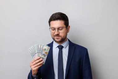 Gri arka planda dolar banknotları olan açgözlü bankacı.