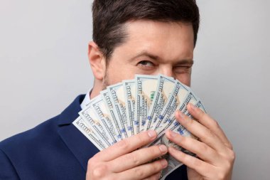 Gri arka planda dolar banknotları olan açgözlü bankacı, yakın plan.