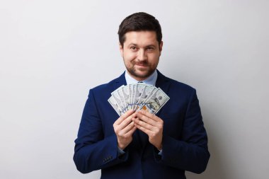 Gri arka planda dolar banknotları olan açgözlü bankacı.