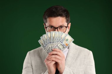 Yeşil arka planda dolar banknotları olan açgözlü bankacı.