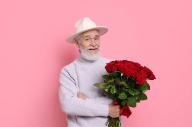 Pembe arka planda kırmızı gül buketi olan son sınıf öğrencisi.