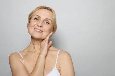 Gri arka planda gülümseyen orta yaşlı kadın portresi. Metin için boşluk