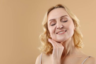 Bej arka planda gülümseyen orta yaşlı kadın. Metin için boşluk