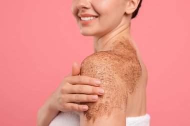 Gülümseyen kadın kolunu pembe arka planda ovalıyor, yakın plan.