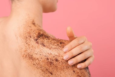 Omuzlarını pembe arka plana sürten kadın, yakın plan.