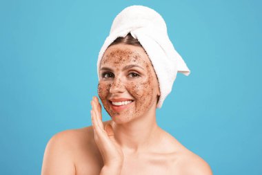 Yüzü açık mavi arka planda gülümseyen bir kadın.