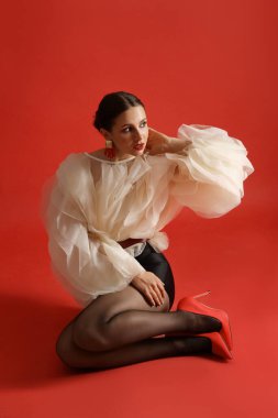 Kırmızı arka planda şık giyinmiş genç bir kadın.