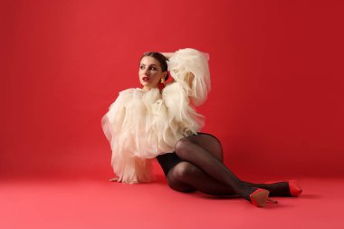 Kırmızı arka planda şık giyinmiş genç bir kadın.