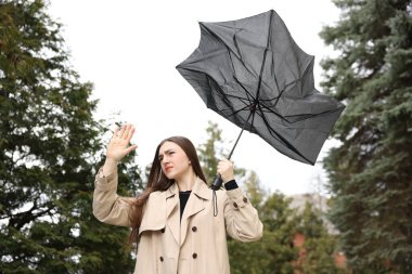 Kırık şemsiyeli bir kadın açık havada rüzgarla dövüşüyor, düşük açılı.
