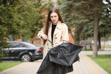 Parkta kırık şemsiyeli üzgün kadın