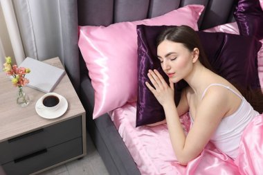 Kadın yatakta ipek çarşaflarla uyuyor.