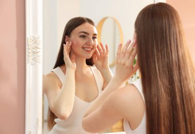 Güzel bir kadın aynada kendine bakıyor.