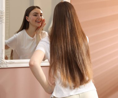 Güzel bir kadın aynada kendine bakıyor.