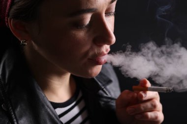 Siyah arka planda sigara içen kadın, yakın plan.