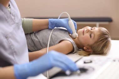 Sonograf, klinikte küçük kızın tiroid bezini ultrason muayenesi yapıyor.