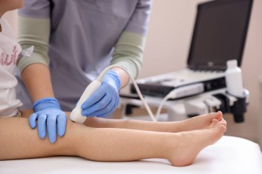 Sonograf, klinikte küçük kızın dizinin ultrason muayenesini yapıyor.