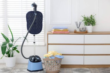 Kapalı alanda temiz çamaşırları olan modern, dik bir buharlı sepet.