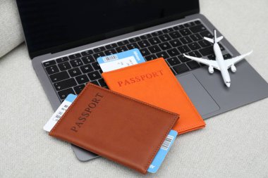 Pasaportlar, uçuş biletleri, uçak modeli ve dizüstü bilgisayar koltukta.