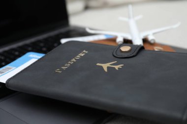 Pasaportlar, uçuş biletleri, uçak modeli ve bulanık arkaplanda dizüstü bilgisayar, yakın plan.