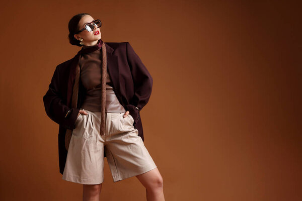 Молодая женщина в стильной одежде на коричневом фоне, пространство для текста