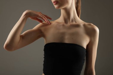 Gri arka planda mükemmel ince vücutlu kadın, yakın plan.