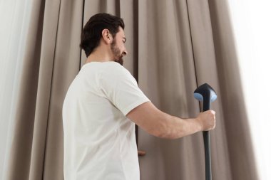 Evde buharlı perdeleri olan bir adam.