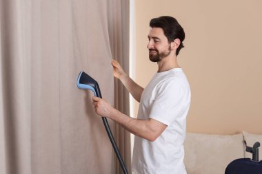 Evde buharlı perdeleri olan bir adam.