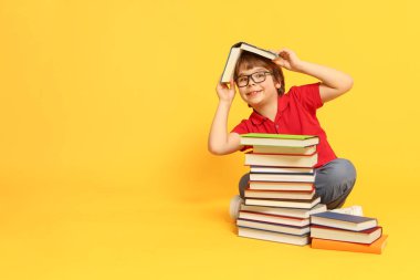 Turuncu arka plan hakkında çok farklı kitapları olan bir çocuk. Metin için boşluk