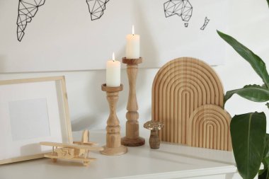 Duvarın yanındaki dolapta yanan mumlar ve diğer dekorlarla süslü şamdanlar.