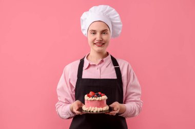 Şekerci pembe arka planda lezzetli bir pasta tutuyor.