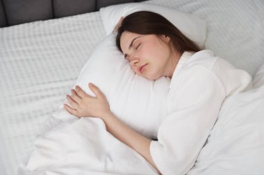 Evde yatakta uyuyan genç kadın.