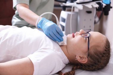 Sonograf, klinikte kızın tiroid bezi ultrason muayenesini yönetiyor.
