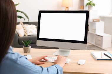 İçerideki ahşap masada boş ekranla monitöre bakan bir kadın. Tasarım için model