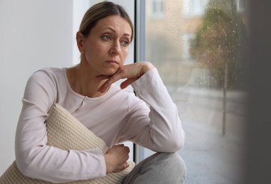 Depresyondaki kadın pencereden dışarı bakıyor, mesaj için boşluk var.