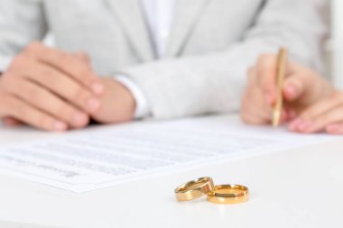 Yeni evliler evlilik sözleşmesi imzalıyor ve masada alyanslar var.