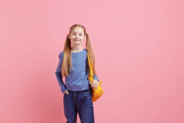 Pembe arka planda sırt çantası olan tatlı bir kız öğrenci.
