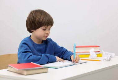 İçeride masa başında ödev yapan sevimli küçük çocuk.