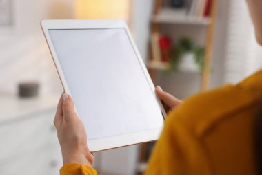 Modern tabletli kadın kapalı mekanda, yakından bakıyor.