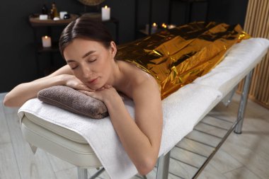Vücuduna termal folyo örten kadın spa salonunda tedavi görüyor.