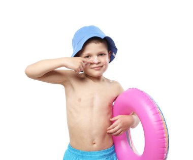 Şişme yüzüklü küçük çocuk beyaz arka planda cildine güneş kremi sürüyor.