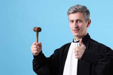 Çekiçle gülümseyen yargıç açık mavi arka planda başparmak gösteriyor. Metin için boşluk