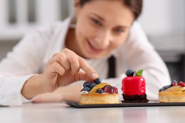 Sofrada yaban mersinli tart dekorasyonu yapan şekerci, seçici odak