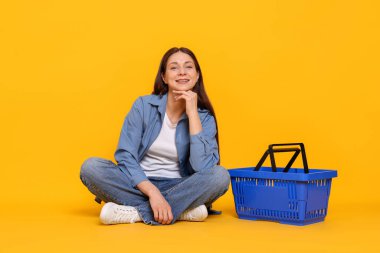 Gülümseyen kadın ve sarı arka planda alışveriş sepeti