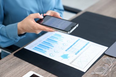 Ofisteki masada akıllı telefondan tarama uygulaması kullanarak belgenin fotoğrafını çeken kadın.