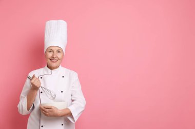 Profesyonel pasta şefi pembe arka planda yemek pişiriyor. Metin için boşluk