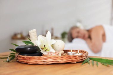 Üst düzey kadın masaj koltuğunda dinleniyor, farklı spa ürünlerine ve zambak çiçeğine odaklanıyor.