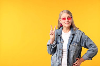 Üst düzey kadın şık giyinmiş turuncu arka planda v işareti gösteriyor, mesaj için yer var.