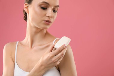 Pembe arka planda sabun çubuğu olan güzel bir kadın. Metin için boşluk