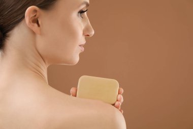 Kahverengi arka planda sabun barı olan bir kadın, yakın plan. Metin için boşluk