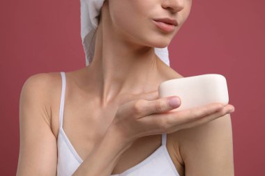 Pembe arka planda sabun barı olan kadın, yakın plan.